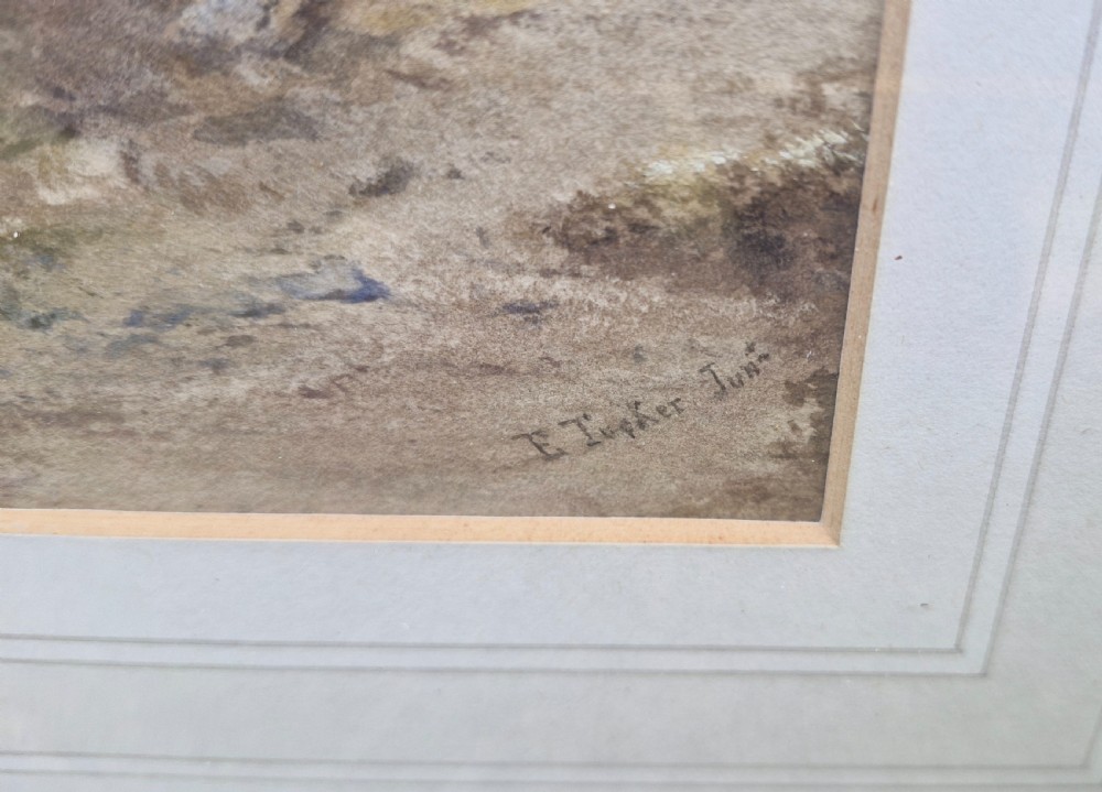 A framed 19th-century watercolour painting depicting a Lake District scene with small boats on a lake surrounded by trees and mountains, enclosed in a cream wash mount and a gilded decorative frame. View V