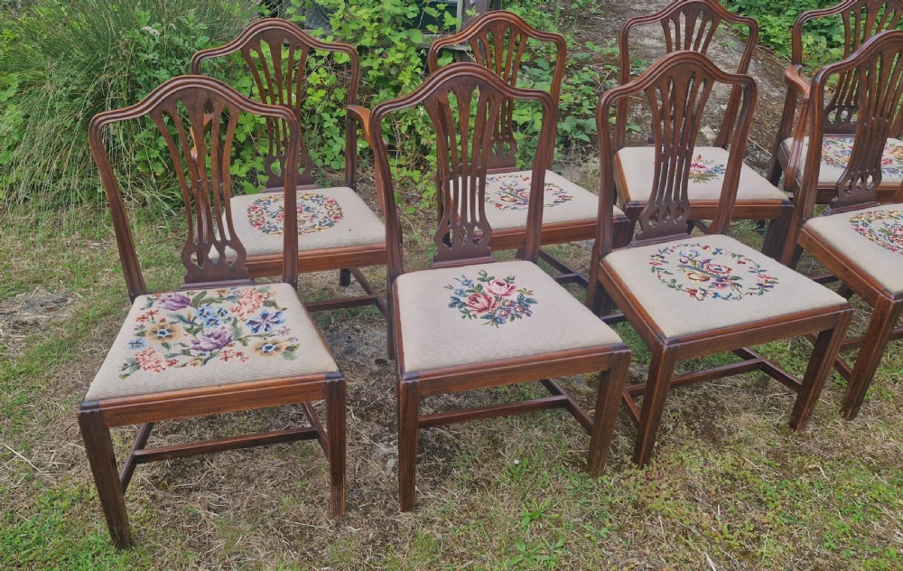 A set of eight dark mahogany dining chairs featuring carved pierced back splats and floral needlework drop-in seats. View II