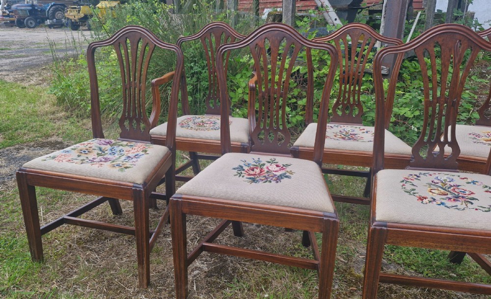 A set of eight dark mahogany dining chairs featuring carved pierced back splats and floral needlework drop-in seats. View V