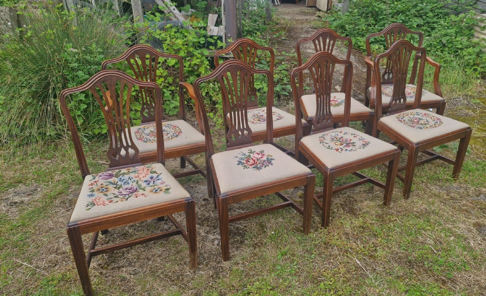 A set of eight dark mahogany dining chairs featuring carved pierced back splats and floral needlework drop-in seats. View VI