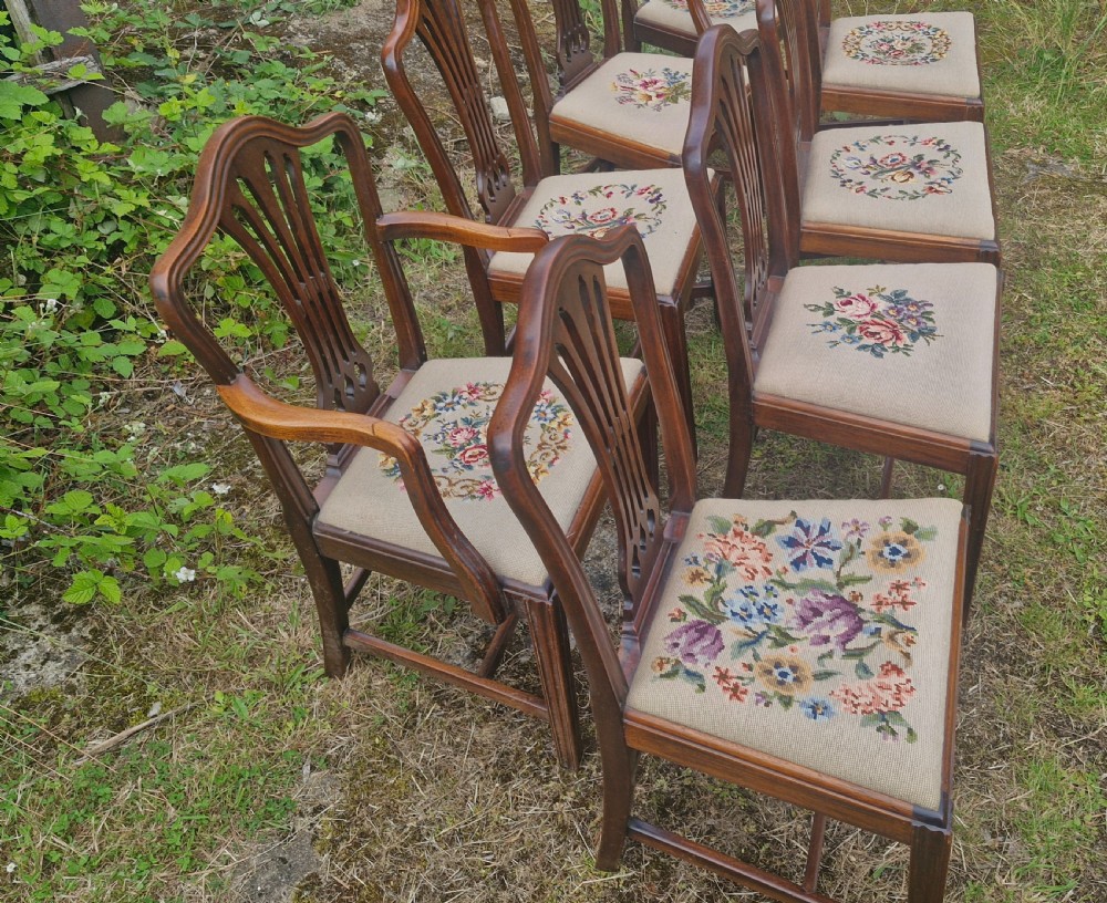A set of eight dark mahogany dining chairs featuring carved pierced back splats and floral needlework drop-in seats. View VII