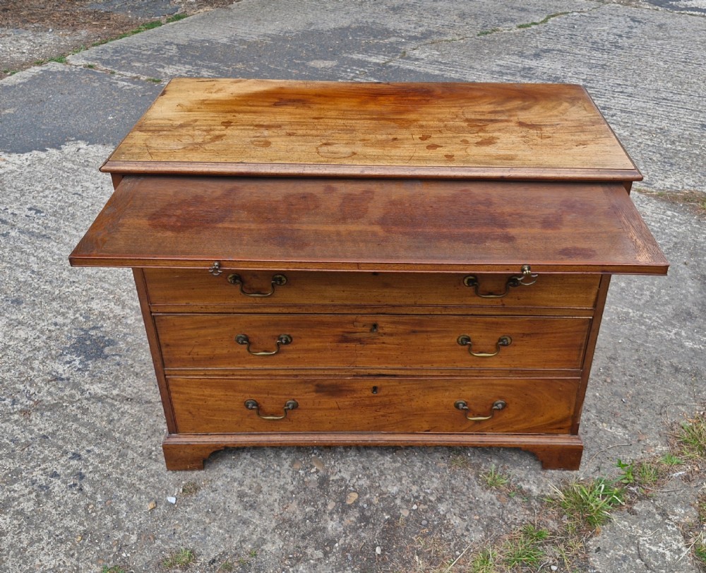An early nineteenth-century mahogany chest of four graduated drawers featuring brass swan-neck handles, key escutcheons, a pull-out brushing slide, and bracket feet. View VI