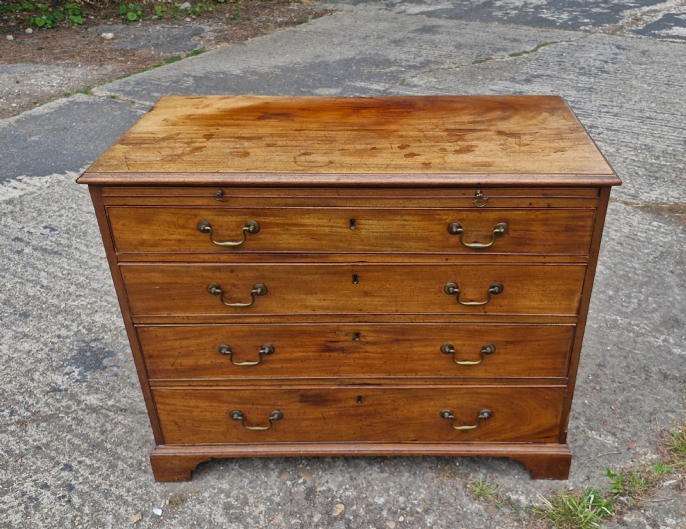 An early nineteenth-century mahogany chest of four graduated drawers featuring brass swan-neck handles, key escutcheons, a pull-out brushing slide, and bracket feet. View VII