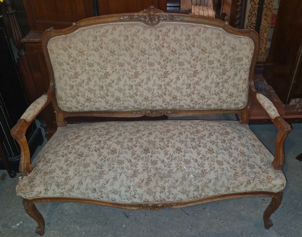 A late 19th-century French walnut canape featuring an exposed carved frame, floral upholstery, padded armrests, and cabriole legs. View II