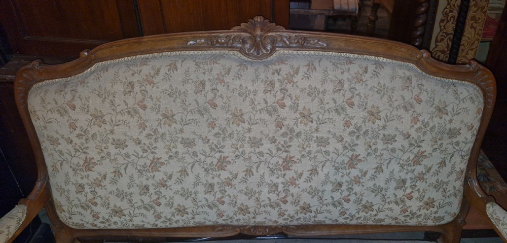 A late 19th-century French walnut canape featuring an exposed carved frame, floral upholstery, padded armrests, and cabriole legs. View VII