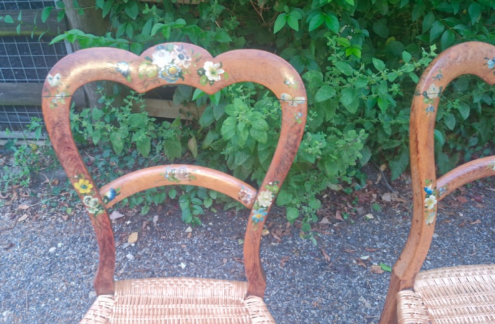 A pair of Victorian side chairs featuring light brown wooden frames adorned with hand-painted floral motifs and woven cane seats. View VII