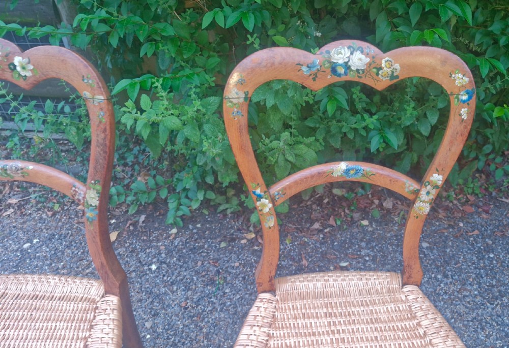 A pair of Victorian side chairs featuring light brown wooden frames adorned with hand-painted floral motifs and woven cane seats. View VIII
