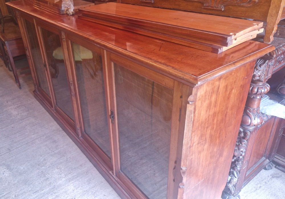 A large late Victorian mahogany low bookcase featuring four glazed glass doors with removable timber shelves resting in front. View VII