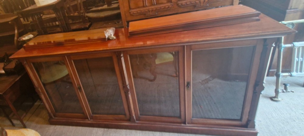 A large late Victorian mahogany low bookcase featuring four glazed glass doors with removable timber shelves resting in front. View VIII