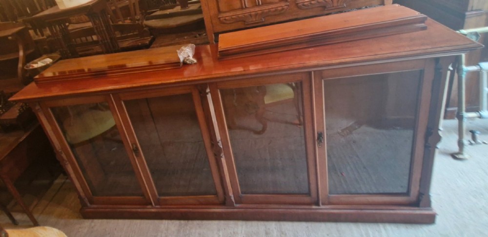 A large late Victorian mahogany low bookcase featuring four glazed glass doors with removable timber shelves resting in front. View X