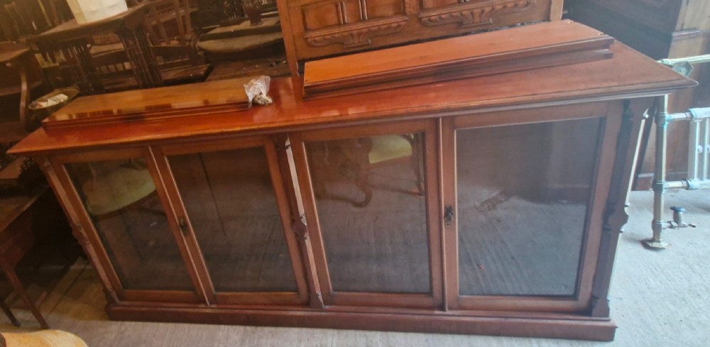 A large late Victorian mahogany low bookcase featuring four glazed glass doors with removable timber shelves resting in front. View XI