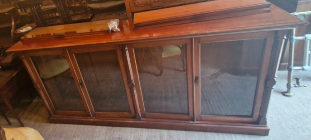 A large late Victorian mahogany low bookcase featuring four glazed glass doors with removable timber shelves resting in front. View XII