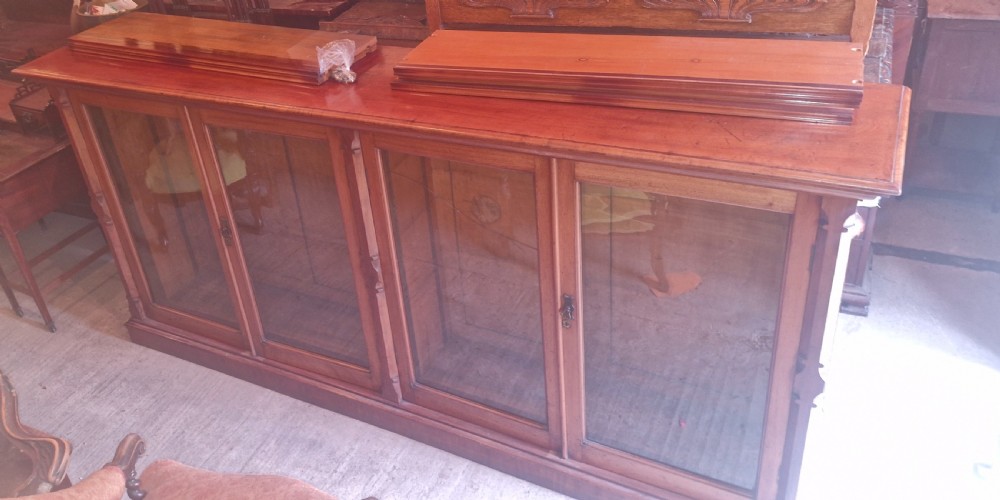 A large late Victorian mahogany low bookcase featuring four glazed glass doors with removable timber shelves resting in front. View XIII