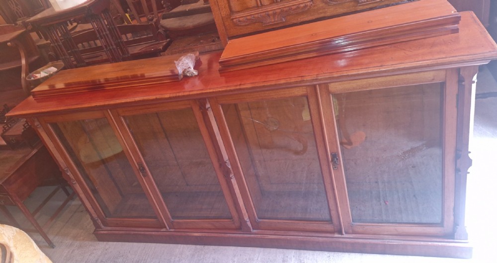 A large late Victorian mahogany low bookcase featuring four glazed glass doors with removable timber shelves resting in front. View XV
