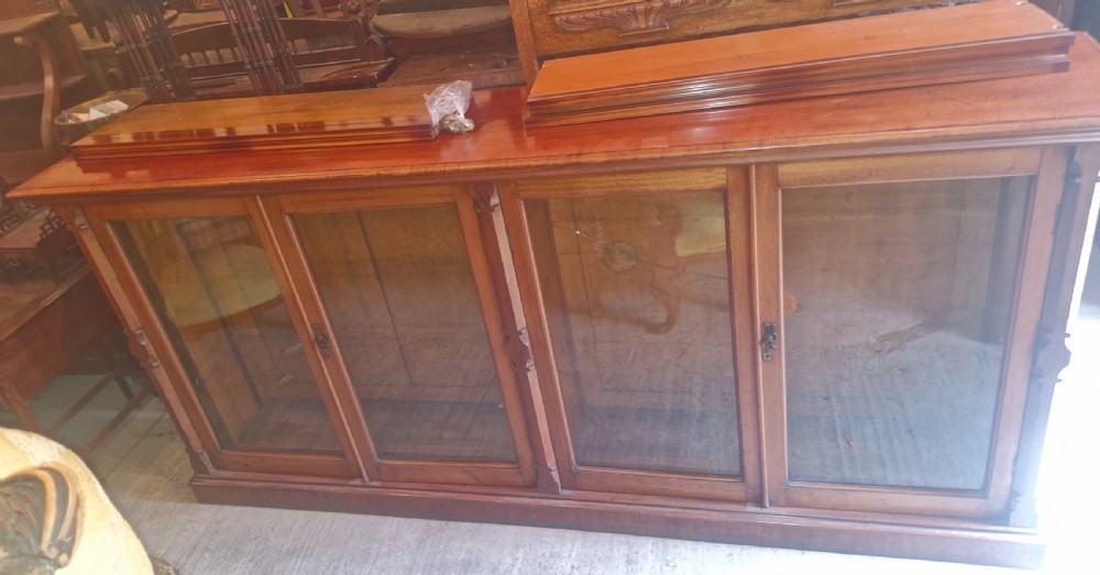 A large late Victorian mahogany low bookcase featuring four glazed glass doors with removable timber shelves resting in front. View XVI