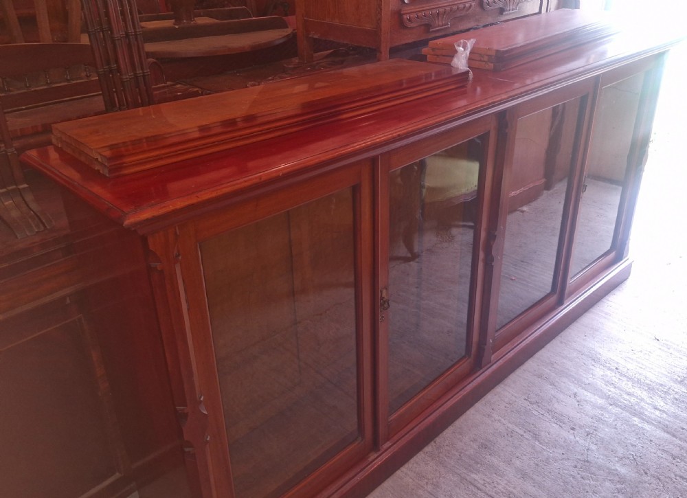 A large late Victorian mahogany low bookcase featuring four glazed glass doors with removable timber shelves resting in front. View XVII