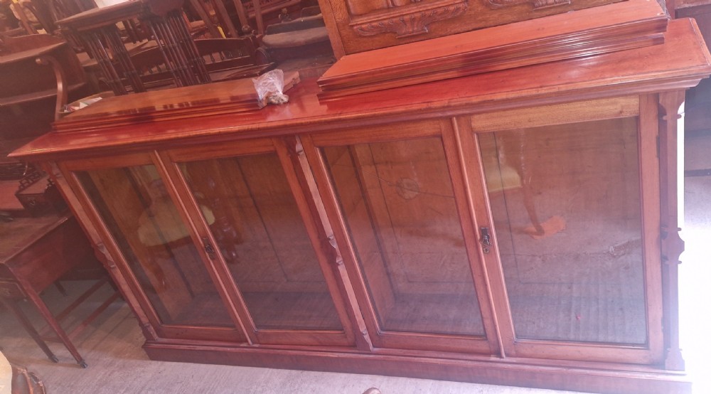 A large late Victorian mahogany low bookcase featuring four glazed glass doors with removable timber shelves resting in front. View XIX