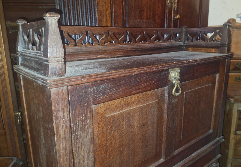 A late Victorian dark oak writing bureau featuring a pierced carved top gallery, fall-front drop lid with brass hardware, and a lower tambour door compartment. View VII