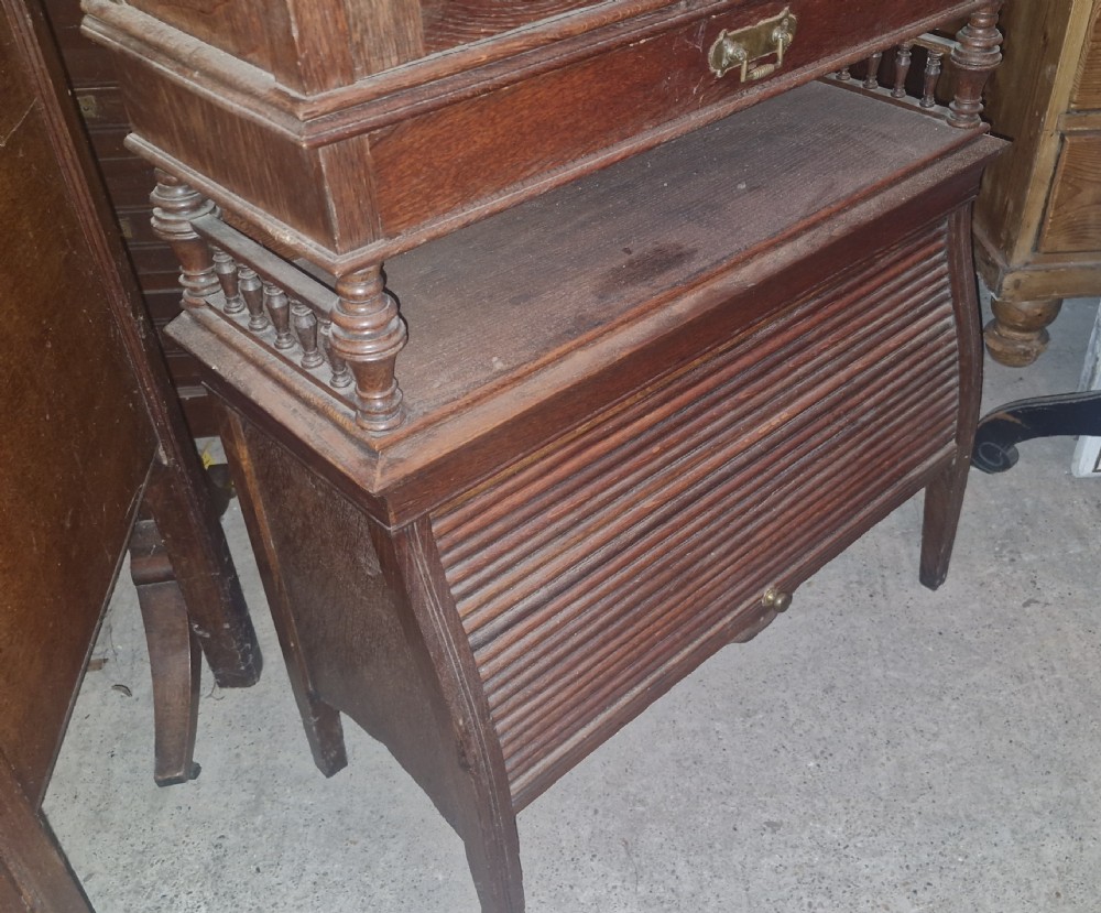 A late Victorian dark oak writing bureau featuring a pierced carved top gallery, fall-front drop lid with brass hardware, and a lower tambour door compartment. View IX