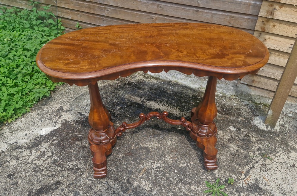 A mid-19th-century mahogany kidney-shaped side table featuring turned pedestal supports, a carved scrolled stretcher, and shaped feet. View II