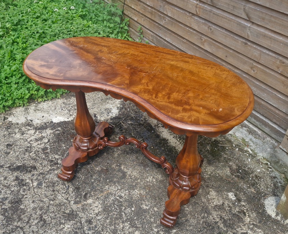 A mid-19th-century mahogany kidney-shaped side table featuring turned pedestal supports, a carved scrolled stretcher, and shaped feet. View V