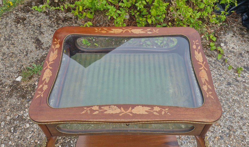 An Edwardian mahogany bijouterie table featuring floral marquetry inlay on the hinged glass top, slender cabriole legs, brass mounts, and a green fabric-lined interior. View III