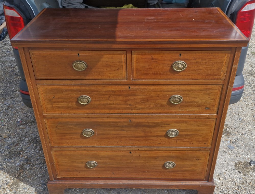 An Edwardian mahogany chest of drawers with linear string inlay borders, two short top drawers, three long lower drawers, and brass oval swing handles. View VIII