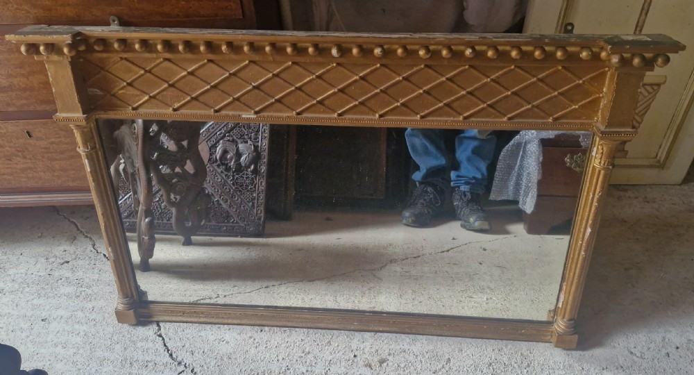 A 19th-century rectangular giltwood overmantel mirror featuring a lattice frieze, ball moulding along the top cornice, and flanking fluted columns.