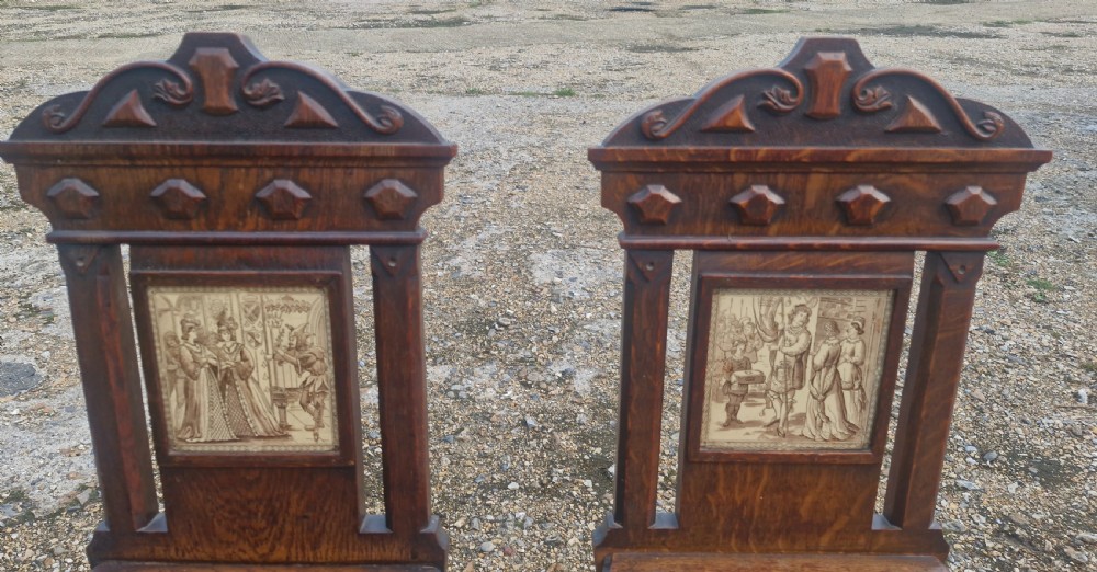 A pair of dark oak hall chairs featuring inset ceramic tiles with historic figures in the backrests, solid seats, and turned front legs. View III