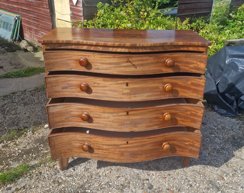 An early 19th-century mahogany serpentine chest of drawers featuring four graduated drawers with turned wooden knobs and a contoured front. View VIII