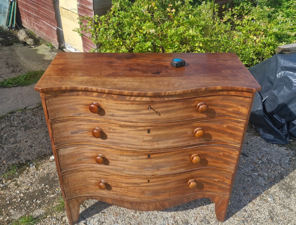 An early 19th-century mahogany serpentine chest of drawers featuring four graduated drawers with turned wooden knobs and a contoured front. View XIII
