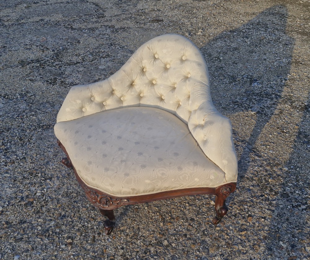 An antique Victorian corner chair featuring cream deep-buttoned damask upholstery, a carved rosewood frame with floral aprons, and curved cabriole legs on castors. View IV