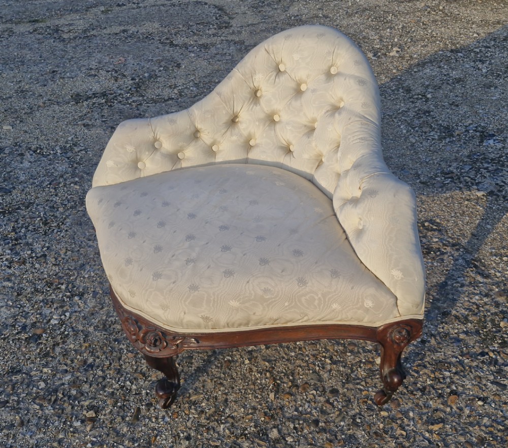 An antique Victorian corner chair featuring cream deep-buttoned damask upholstery, a carved rosewood frame with floral aprons, and curved cabriole legs on castors. View VII