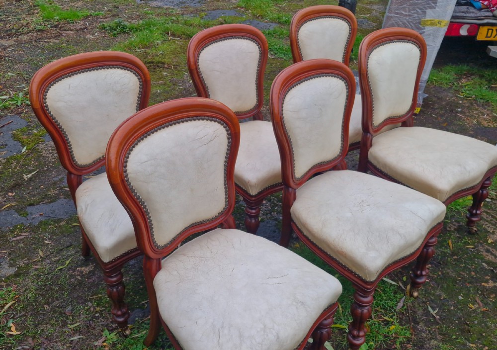 A set of six mid-Victorian mahogany dining chairs with cream upholstered balloon backs, brass studding, and turned front legs on castors. View VIII