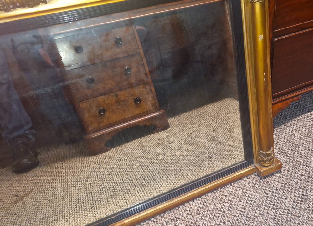 A 19th-century rectangular giltwood overmantel mirror featuring side pilasters, rosette corner mounts, and an ebonised inner slip. View II