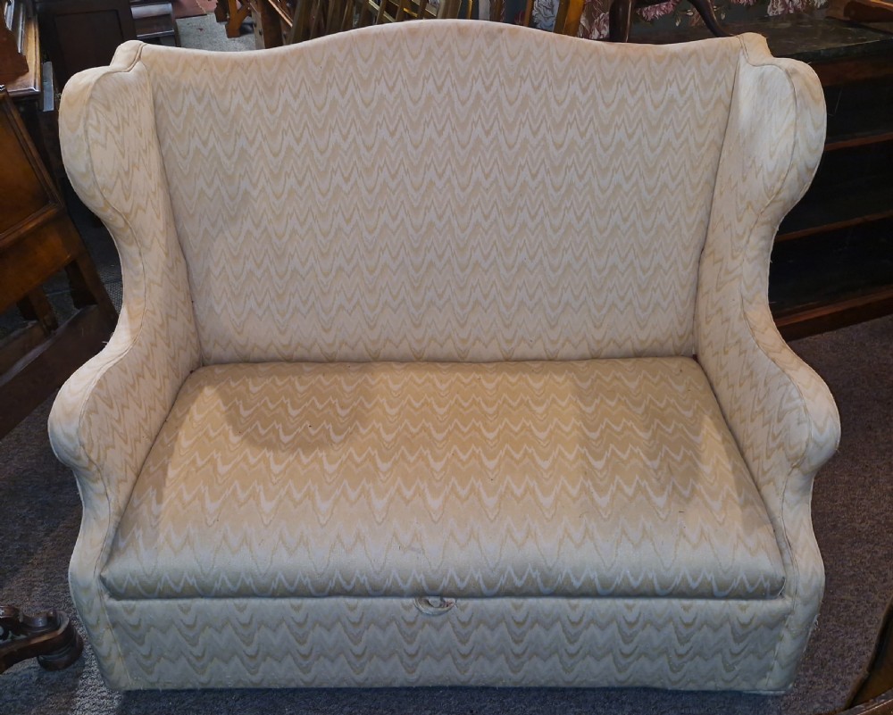 A high-backed two-seater wingback sofa upholstered in cream chevron patterned fabric with an enclosed storage box base. View VI