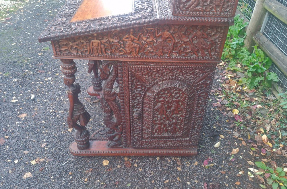 A dark hardwood Davenport writing desk featuring high-relief foliate carvings, figural supports, and a sloped writing lid. View VIII