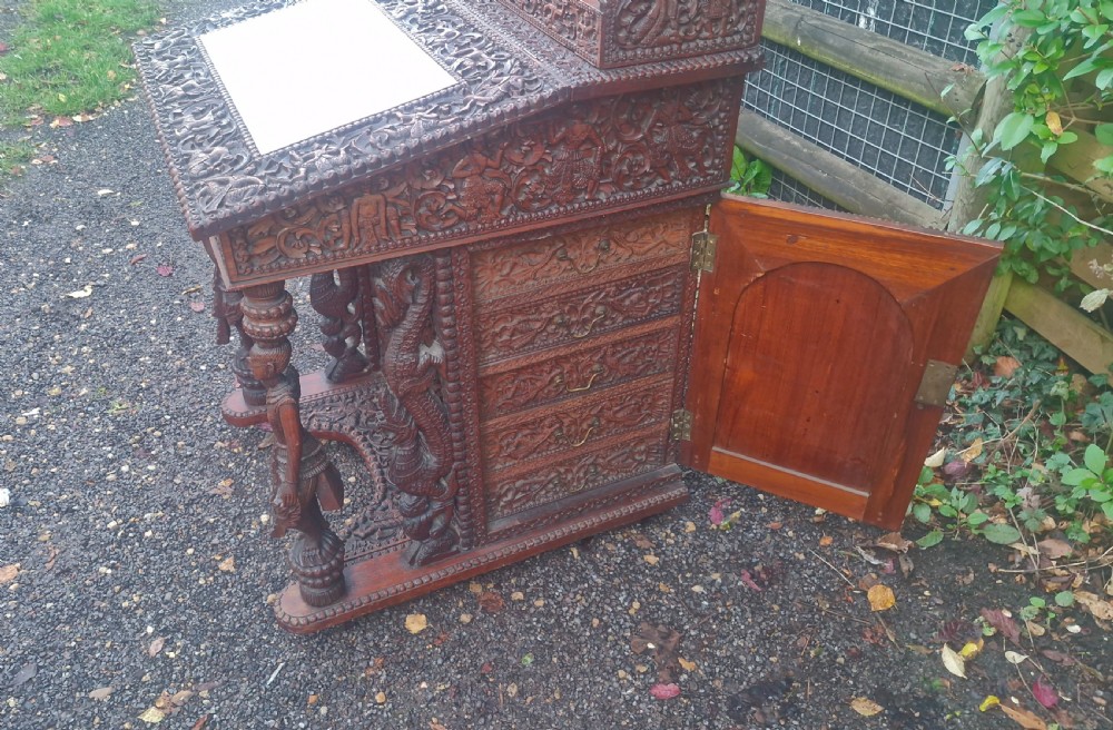 A dark hardwood Davenport writing desk featuring high-relief foliate carvings, figural supports, and a sloped writing lid. View XI