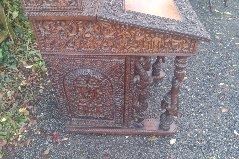 A dark hardwood Davenport writing desk featuring high-relief foliate carvings, figural supports, and a sloped writing lid. View XII