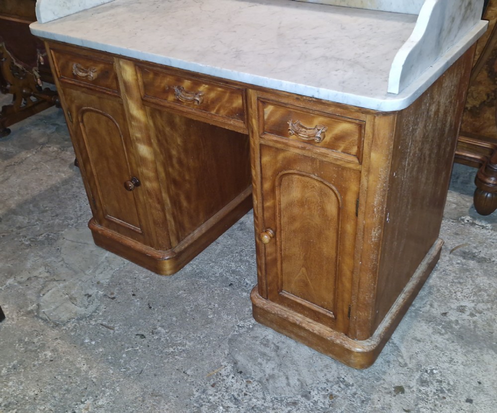 A Victorian satinbirch pedestal washstand featuring a fitted white marble surface with a raised splashback gallery and twin cupboard pedestals. View II