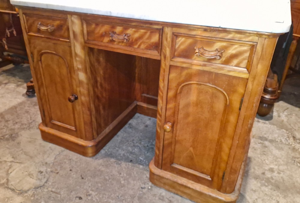 A Victorian satinbirch pedestal washstand featuring a fitted white marble surface with a raised splashback gallery and twin cupboard pedestals. View V