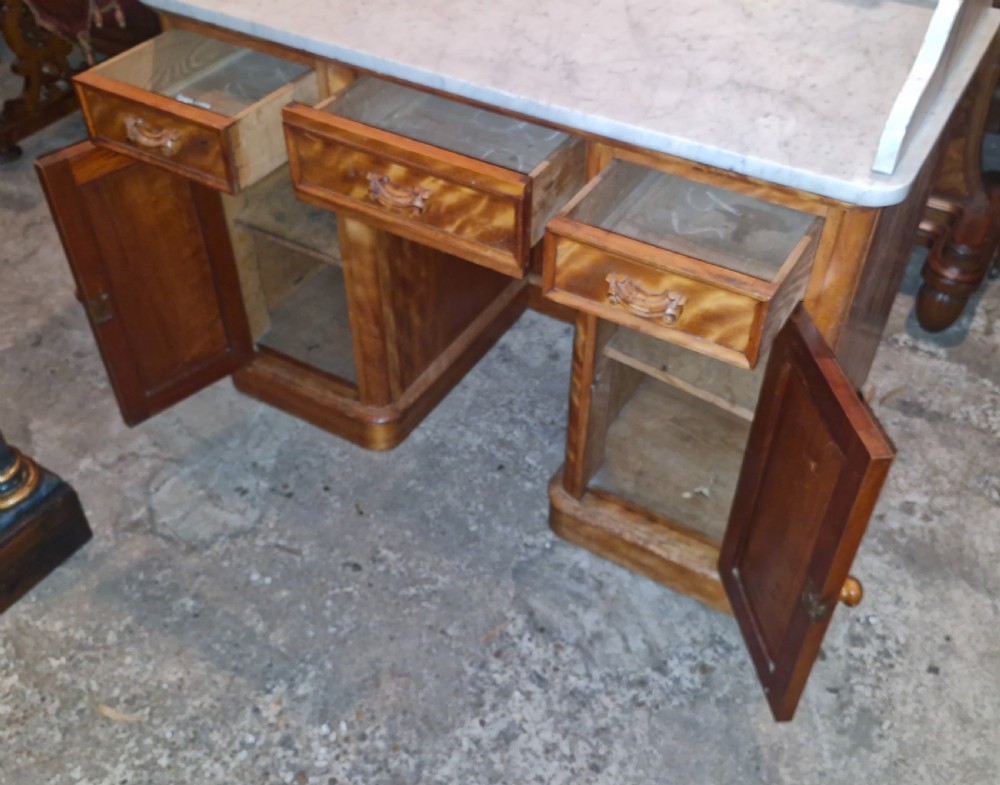 A Victorian satinbirch pedestal washstand featuring a fitted white marble surface with a raised splashback gallery and twin cupboard pedestals. View VI