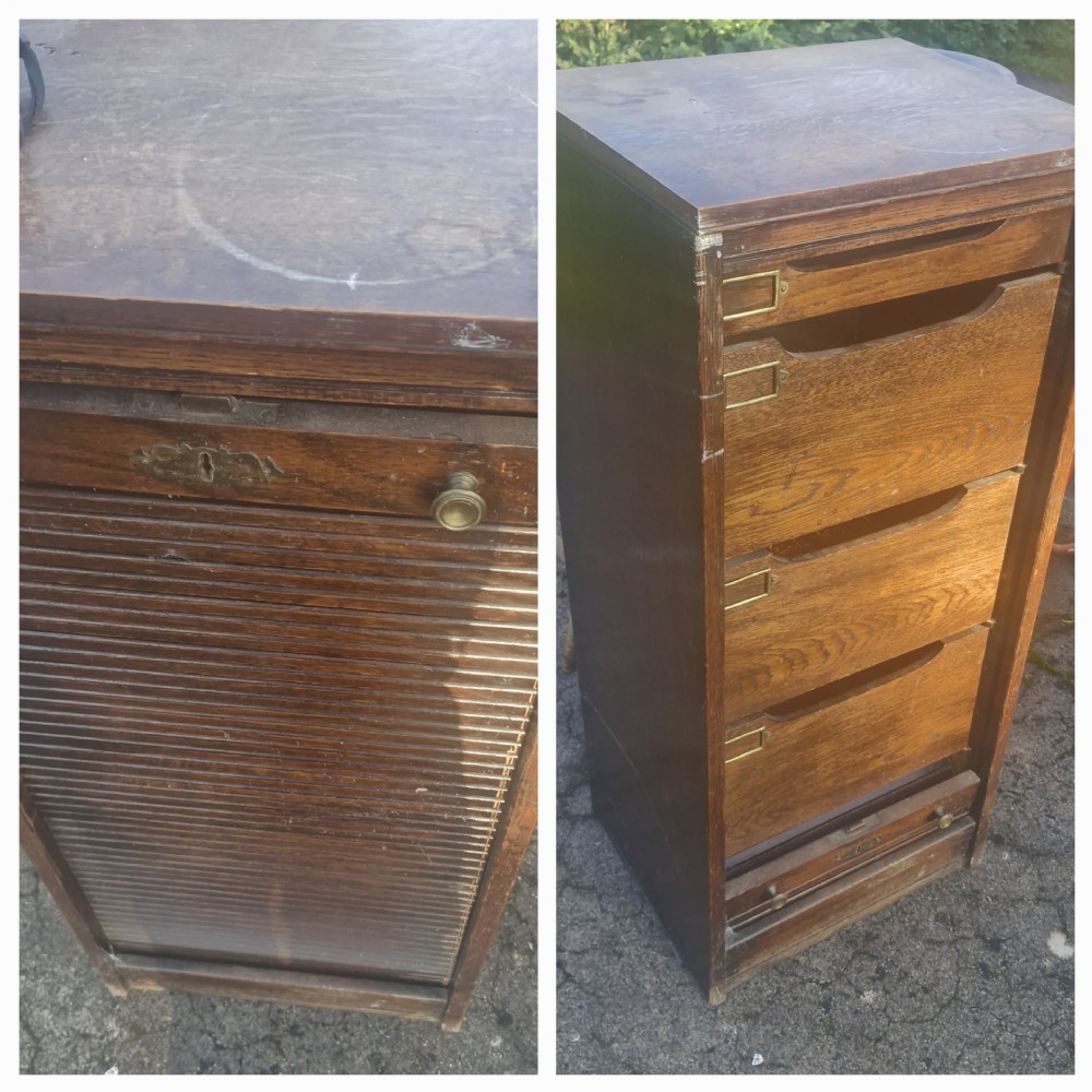 A medium brown oak filing cabinet featuring a slatted roll-down tambour door that opens to reveal internal drawers with brass index card holders.