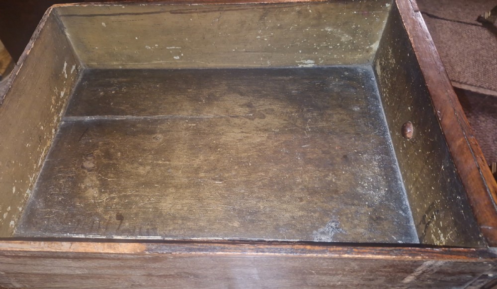An early eighteenth-century dark oak chest of drawers featuring carved mouldings and wooden turned knobs. View V