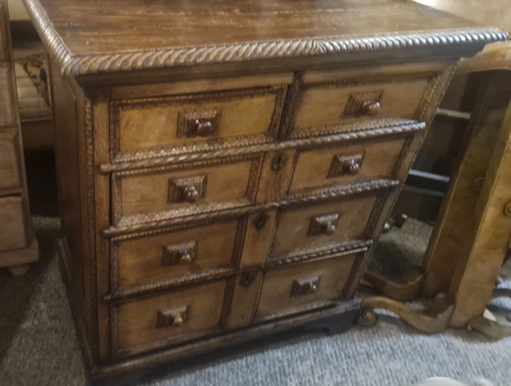 An early eighteenth-century dark oak chest of drawers featuring carved mouldings and wooden turned knobs. View VIII