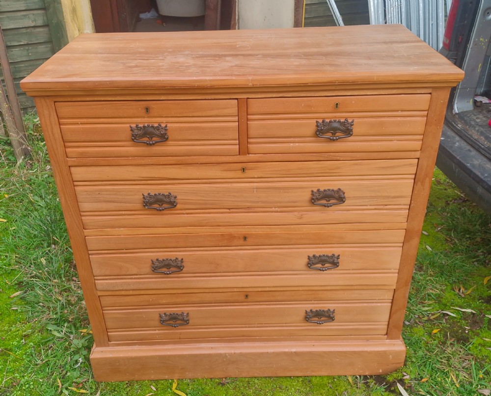 An Edwardian satin walnut chest of drawers featuring two short over three long drawers with horizontal reeded detailing and metal drop handles. View VIII