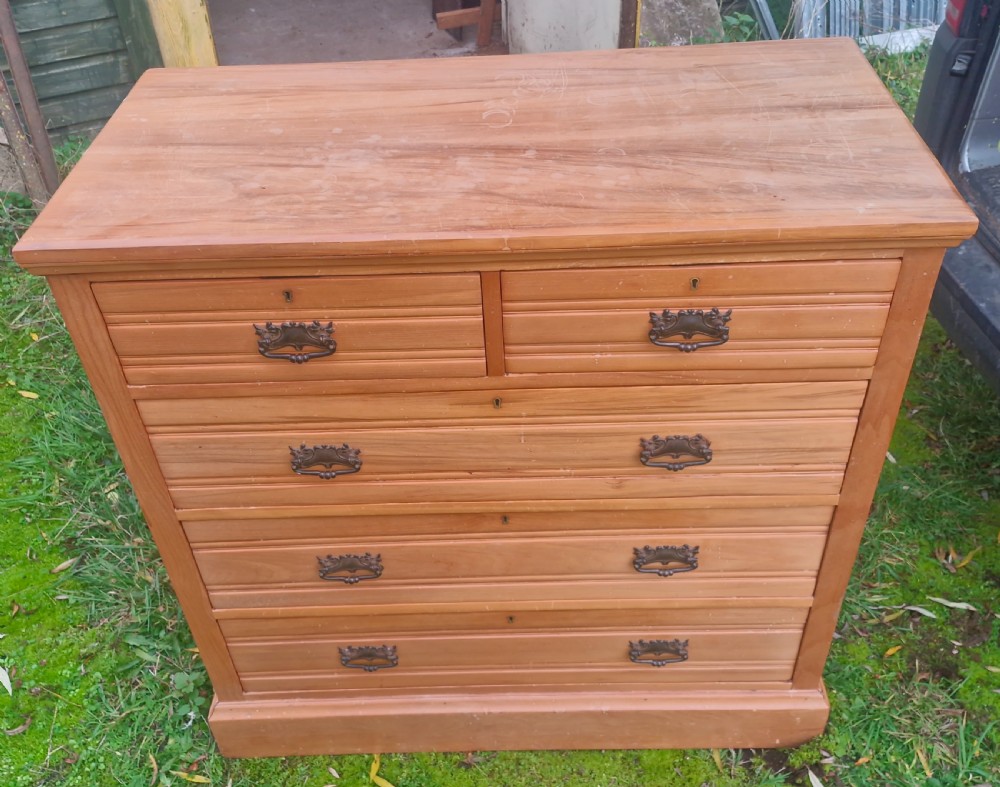 An Edwardian satin walnut chest of drawers featuring two short over three long drawers with horizontal reeded detailing and metal drop handles. View IX