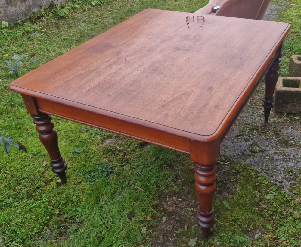 A square Victorian wooden kitchen dining table featuring turned legs fitted with brass castors. View II
