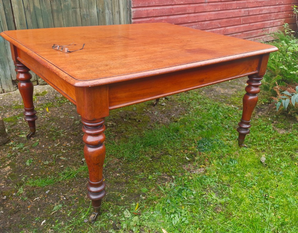 A square Victorian wooden kitchen dining table featuring turned legs fitted with brass castors. View V