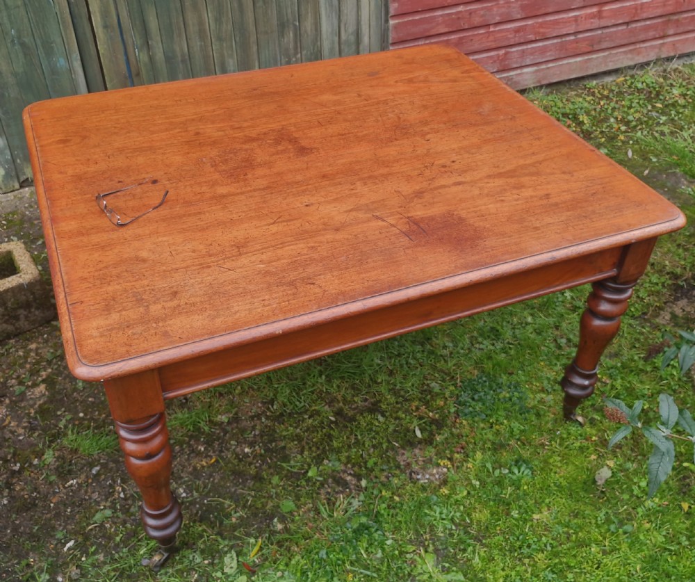 A square Victorian wooden kitchen dining table featuring turned legs fitted with brass castors. View VI
